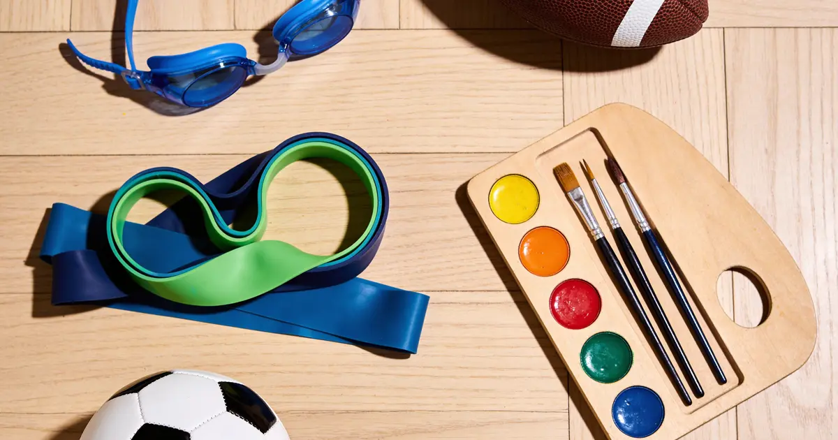Overhead flat-lay of children's sports and craft equipment on a wooden floor, illustrating children's activities Surrey families can choose from